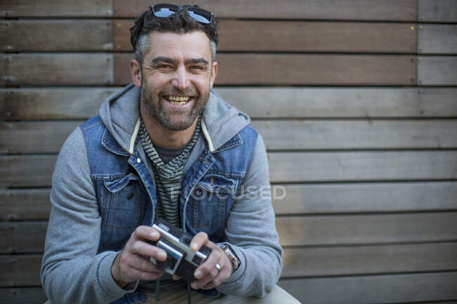 Retrato de homem adulto médio, segurando câmera, sorrindo — Fotografia de Stock