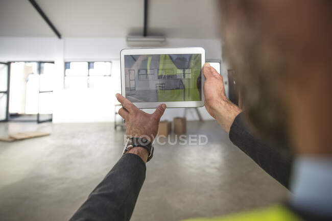 Людина фотографує порожній офісний простір з цифровим планшетом — стокове фото