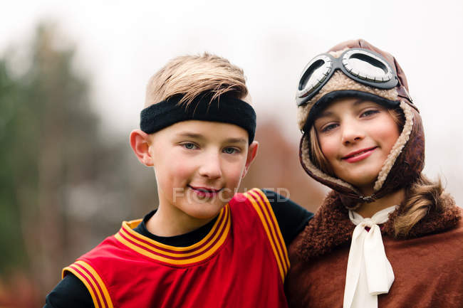 Retrato de niño y hermana gemela vistiendo trajes de baloncesto y piloto para Halloween - foto de stock