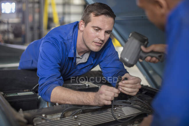 Mécanique automobile inspectant le moteur de voiture dans le garage de réparation — Photo de stock