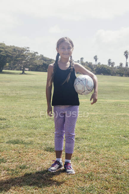 Portrait of schoolgirl holding soccer ball on school sports field — Stock Photo