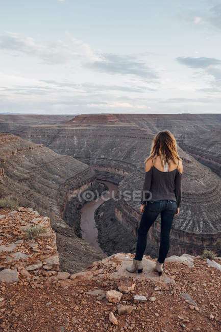 Молодая женщина, стоящая на краю скалы и смотрящая на вид, Мексиканская шляпа, Юта, США — стоковое фото