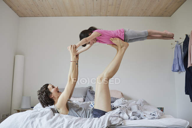 Mãe e filha brincando na cama no quarto leve — Fotografia de Stock