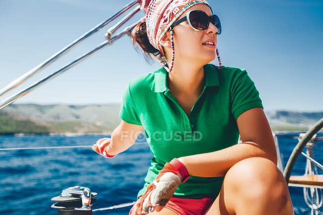 Young woman crouching on yacht near coast, Croatia — Stock Photo