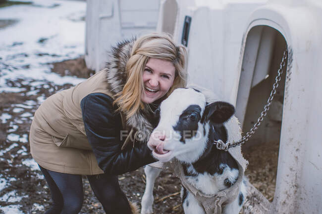 Portrait of young woman with cow, in winter landscape — Stock Photo