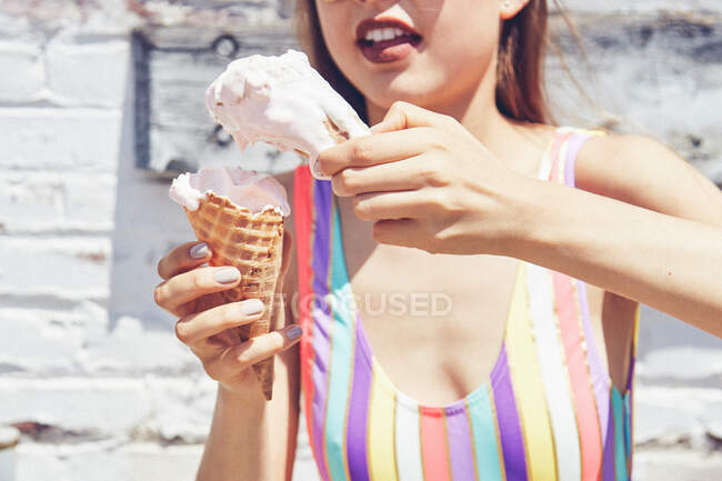 Jeune femme tenant deux cônes de crème glacée fondante, recadrée — Photo de stock