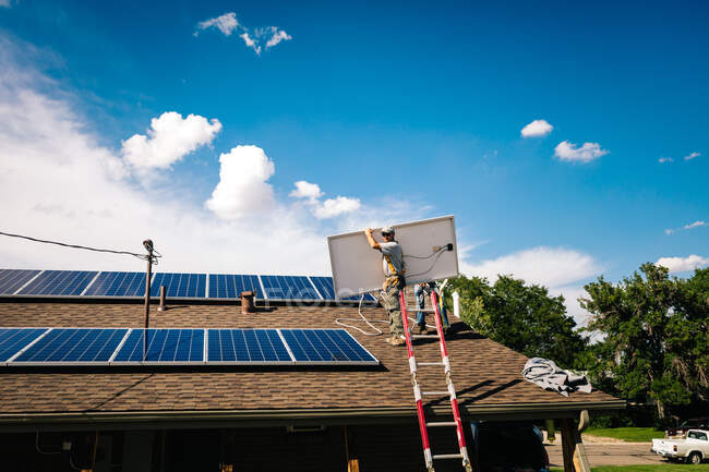 Працівники встановлюють сонячні панелі на даху будинку, низький кут огляду — стокове фото