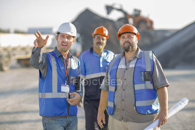 Three quarry workers in discussion, at quarry site — Stock Photo