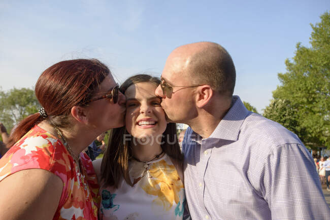 Parents kissing daughter at graduation ceremony — Stock Photo