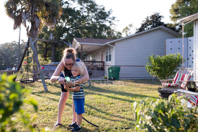 Mother and son in garden with hosepipe — Stock Photo