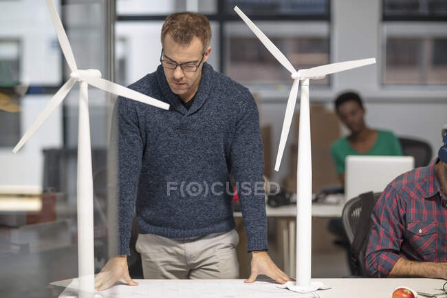 Людина в офісі дивлячись на архітектурну модель вітрових турбін — стокове фото