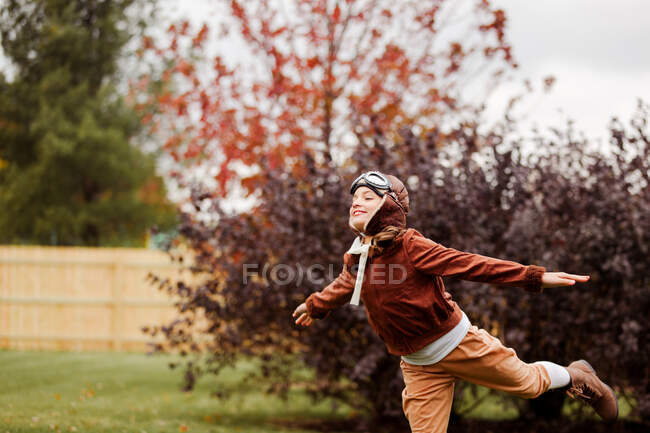 Дівчина в пілотному костюмі для Хеллоуїна з відкритими руками в парку — стокове фото