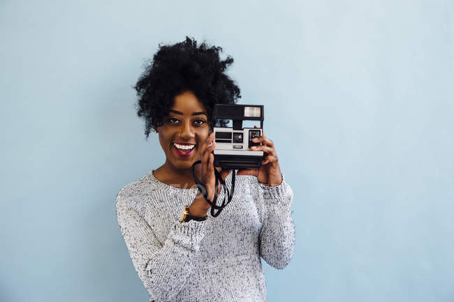 Woman with instant camera smiling at camera — Stock Photo