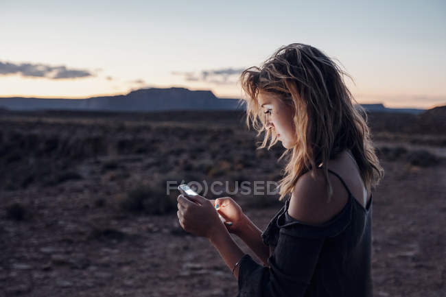Mujer joven usando smartphone, Mexican Hat, Utah, EE.UU. - foto de stock