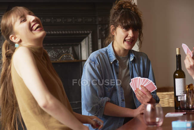 Друзья смеются и играют в карты в гостиной — стоковое фото