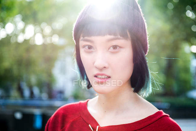 Portrait de jeune femme élégante en bonnet tricoté dans le parc de la ville — Photo de stock