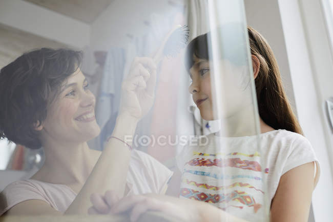 Мать расчесывание дочери волосы в ванной комнате — стоковое фото