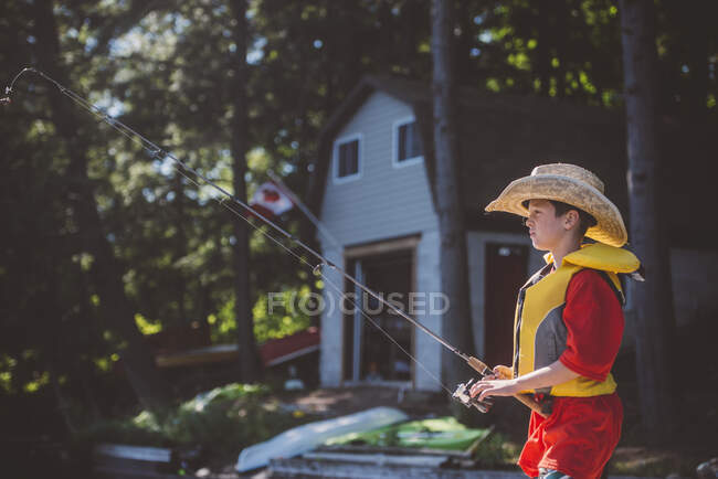 Menino em cowboy chapéu de pesca do lado do lago — Fotografia de Stock