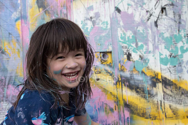 Portrait de fille par mur peint regardant la caméra souriant — Photo de stock