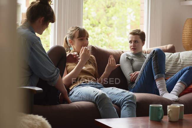 Три молоді жінки спілкуються на дивані — стокове фото