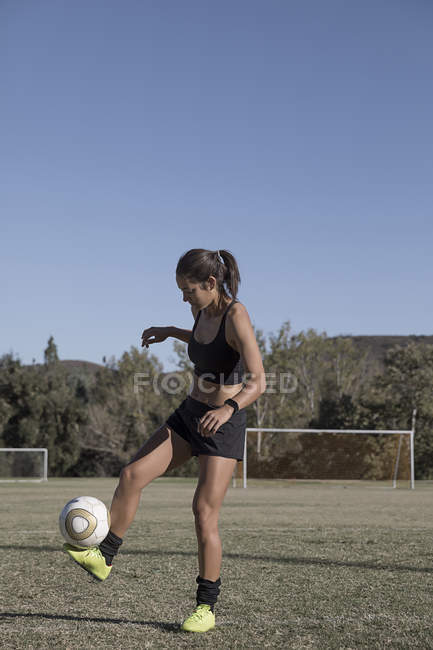 Молода жінка на футбольному полі з футболом — стокове фото