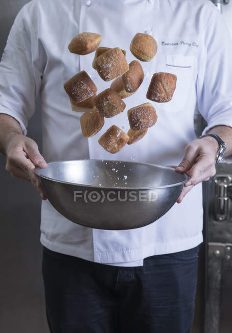 Vue recadrée du chef jetant beignets et sucre dans un bol à mélanger — Photo de stock