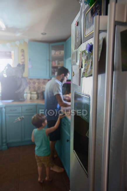 Хлопчик, що стоїть за татом на кухні. — стокове фото