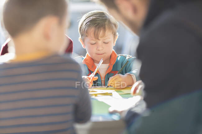 Group of people, outdoors, doing crafting activity, focus on young boy in background — Stock Photo