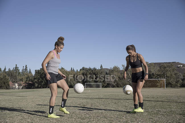 Two women on football pitch playing football — Stock Photo