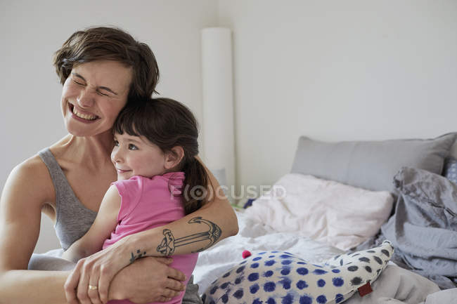 Мати і дочка обіймаються в світлій спальні — стокове фото