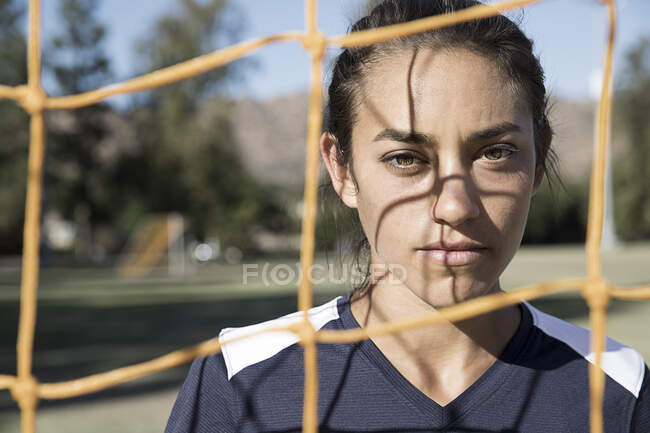 Portrait de femme derrière le filet de but de football en regardant la caméra — Photo de stock