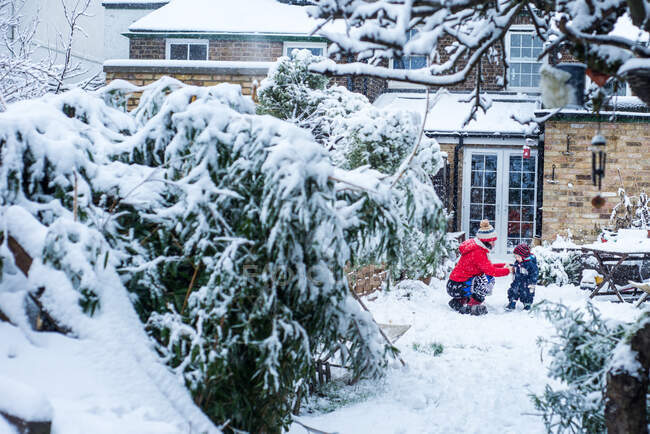 Madre e figlio in giardino a giocare nella neve — Foto stock