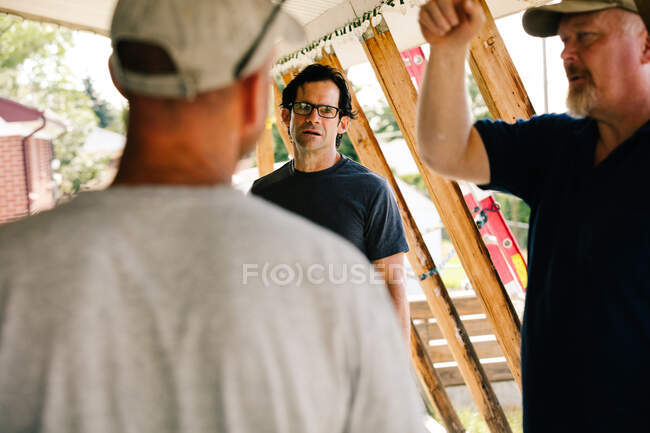 Electricians having discussion in porch, over shoulder view — Stock Photo