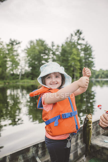 Father and daughter in boat on lake, daughter holding caught fish on line — Stock Photo