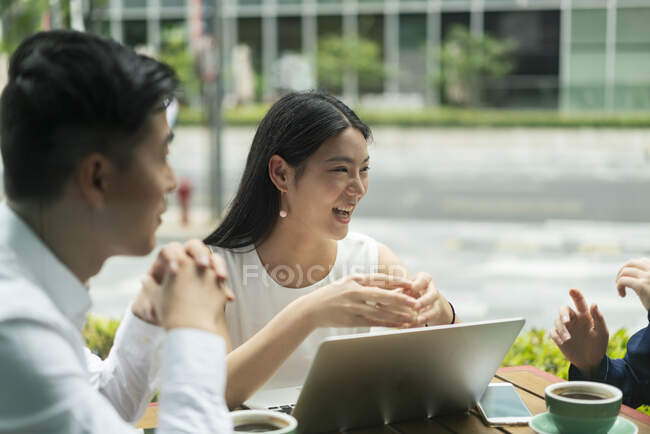 Group of businesspeople, having meeting at cafe, using laptop, outdoors — Stock Photo