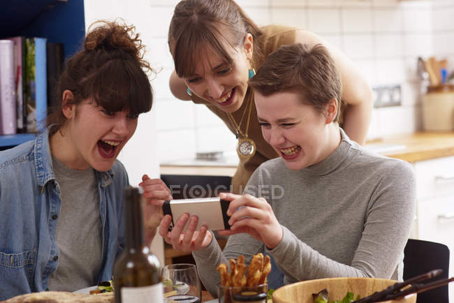 Friends laughing and looking at mobile phone — Stock Photo
