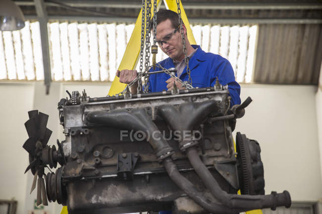 Mechaniker mit Schraubenschlüssel am Automotor in Werkstatt — Stockfoto