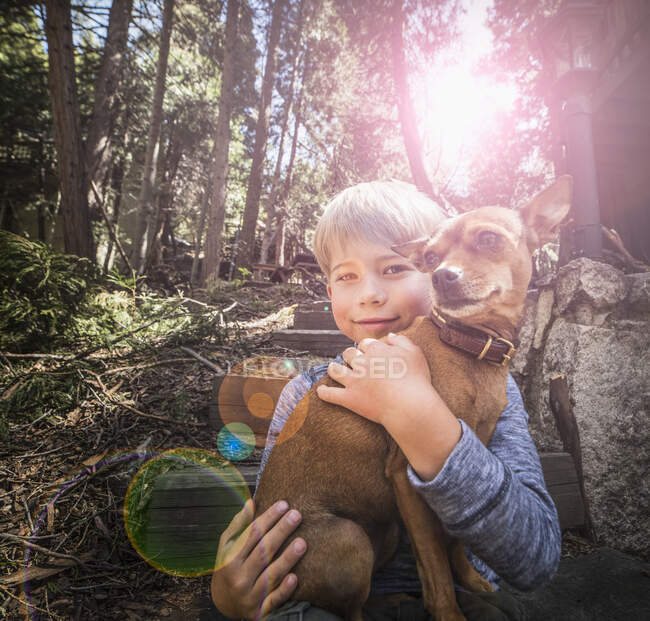 Niño llevando perro en el bosque - foto de stock
