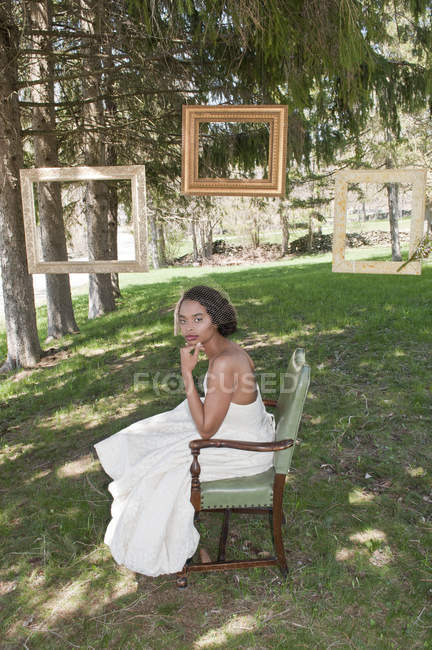 Портрет невесты в свадебном платье, сидящей в кресле на открытом воздухе — стоковое фото
