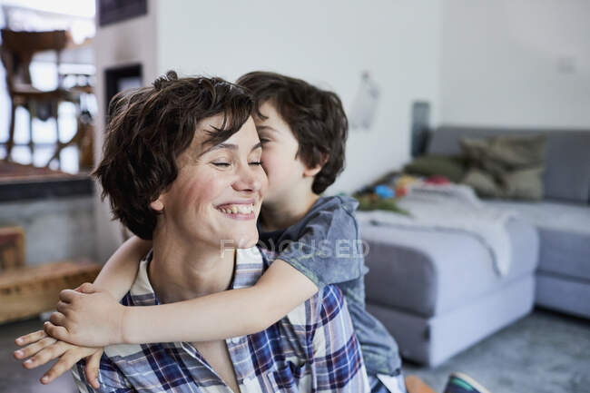 Madre e hijo en casa, hijo abrazando a la madre - foto de stock