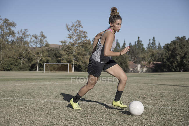 Mulher em campo de futebol jogando futebol — Fotografia de Stock