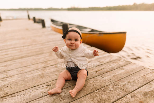 Portrait of baby girl sitting on lake pier — Stock Photo
