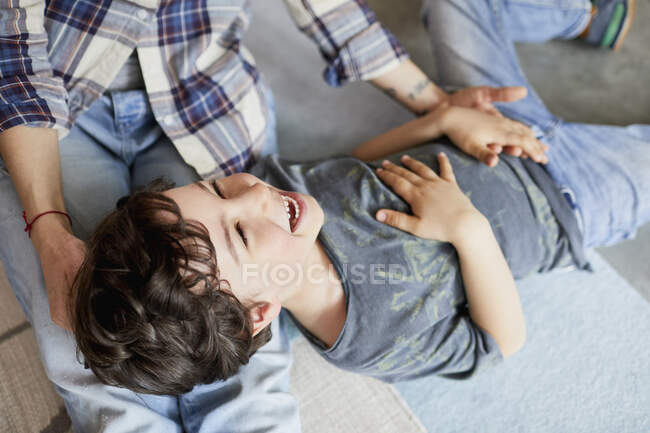 Madre e hijo en casa, hijo acostado en las piernas de la madre - foto de stock