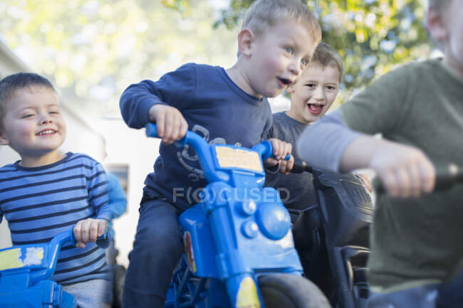 Chicos en carreras preescolares empujan motos en el jardín - foto de stock