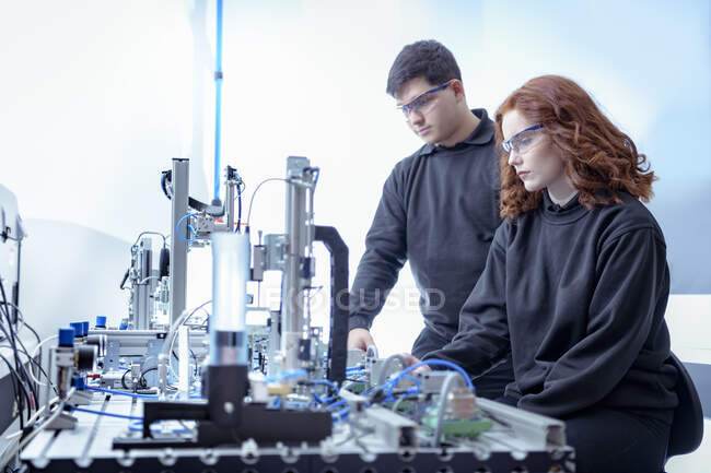 Robotics apprentices with production line simulation in robotics facility — Stock Photo
