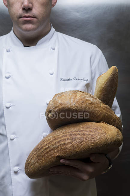 Cropped view of chef holding loaves of bread — Stock Photo