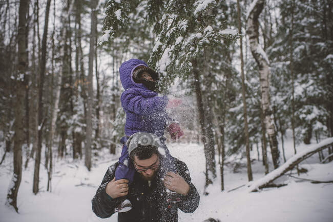 Padre e hija en el paisaje nevado, padre llevando a la hija en hombros - foto de stock