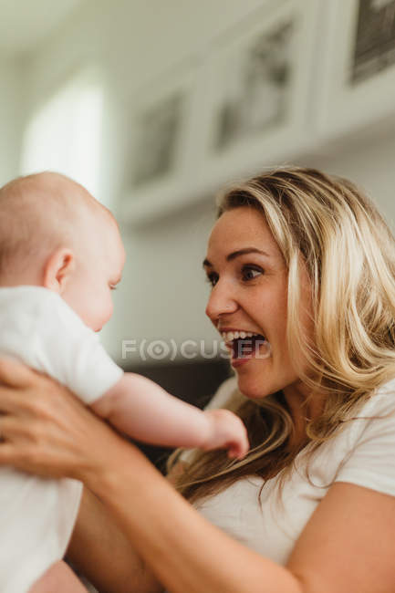 Mãe sorrindo para o bebê filha cara a cara — Fotografia de Stock