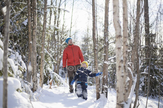 Man and son looking up while walking on winter forest — Stock Photo