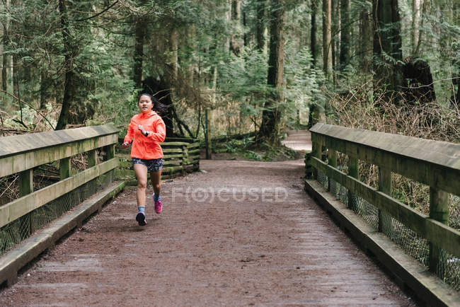 Vista frontal de la mujer corriendo en el bosque, Vancouver, Canadá - foto de stock